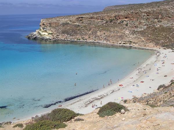 Rabbit Beach, Lampedusa: swimmers on white sand between cliffs and turquoise water