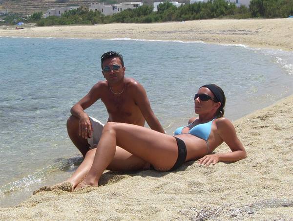 Man and woman in bikini lying on wet sand, turquoise water and white houses