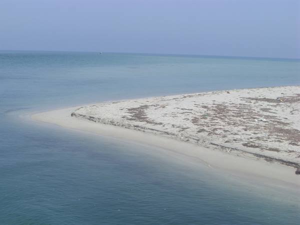 White sand spit surrounded by turquoise sea under clear sky