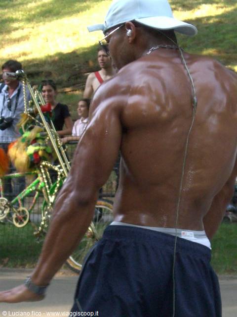 Shirtless muscular man with earphones dancing in a park