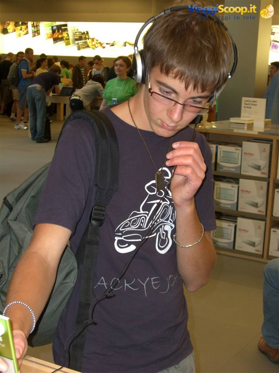 Teenager wearing headphones listens to music in a crowded Apple Store