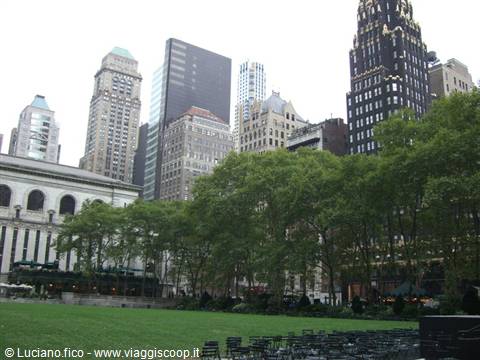 Bryant Park in New York: green lawn, trees and skyscrapers under gray sky