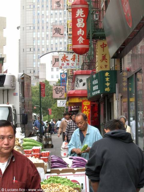 New York's Chinatown: vendor preparing vegetables among Chinese signs and skyscrapers