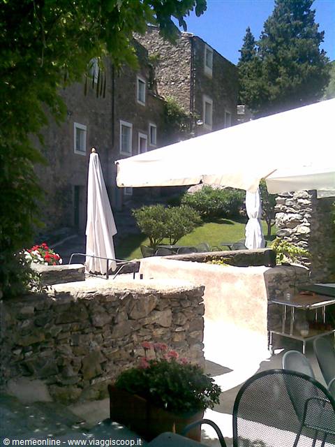 White umbrellas and tables among stone walls and old houses