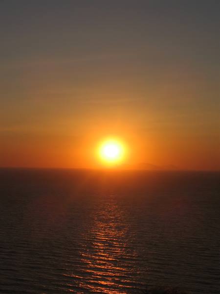 Low sun sinking over the sea, glowing golden reflection on calm water