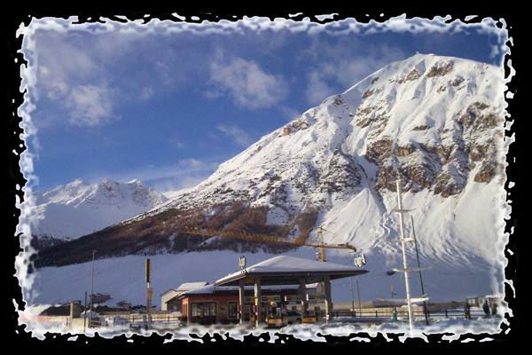 Snow-covered gas station and yellow crane beneath a huge snowy mountain