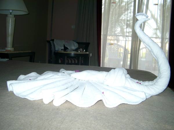 Towel swan folded from white towels on hotel bed, balcony light