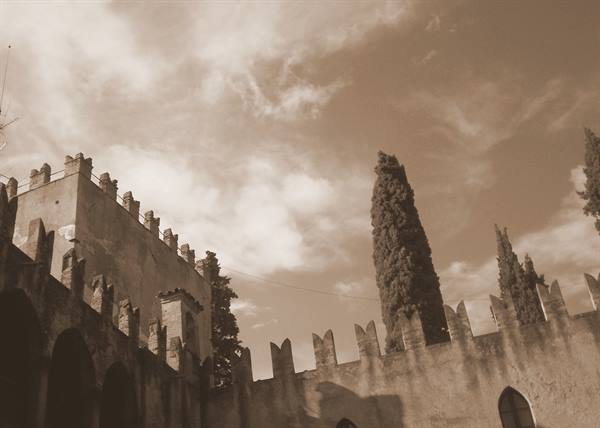 Swallowtail battlements and cypress against a cloudy sky