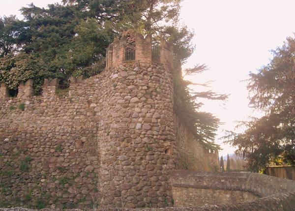 Merlon stone river-rock tower amid conifers, warm filtered light