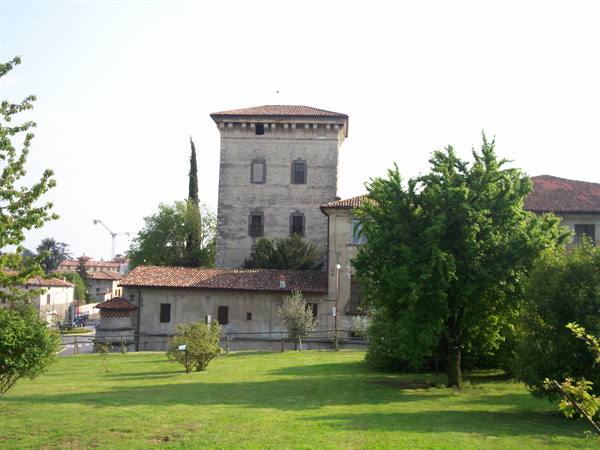 Old stone tower with tiled roof among trees and green lawn