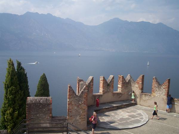 Tourists walk along brick battlements of Malcesine Castle above Lake Garda