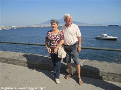Elderly couple strolling along Naples waterfront, Mount Vesuvius in the background
