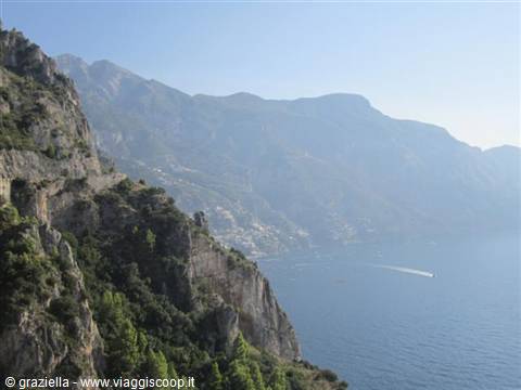 Amalfi Coast: green cliffs above the sea, Positano in the haze, a motorboat passing