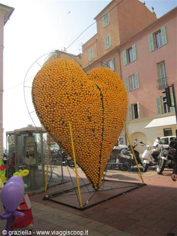 Giant lemon heart sculpture in Menton, between pink buildings and scooters