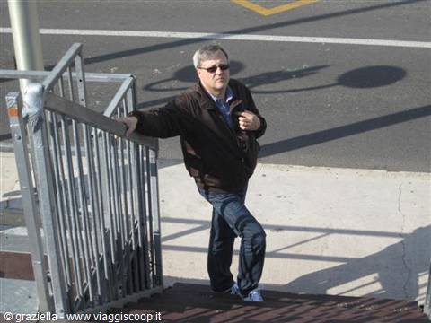 man in sunglasses and brown jacket descending outdoor metal stairs