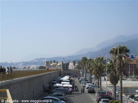 Menton seafront promenade with palm trees, market stalls and coastal castle