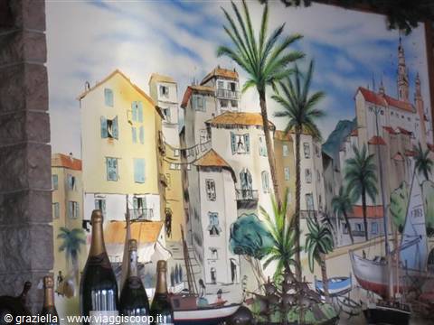 Sparkling wine bottles in front of a painted mural of Mediterranean houses and palms