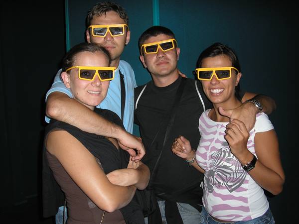 Four friends wearing yellow 3D glasses smiling at the cinema museum