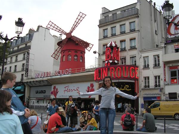 Smiling woman in front of the Moulin Rouge in Paris with red windmill