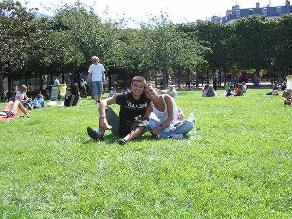 Couple sitting on the lawn in a busy garden, trees and Paris rooftops