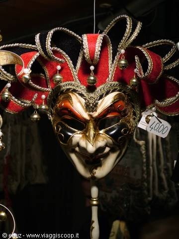 Venetian jester mask in red and gold hanging in a shop