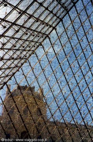 The glass grid of the Louvre Pyramid reflects the museum and sky