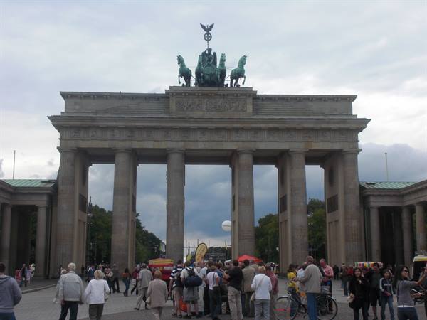Tourists beneath the stone columns of the Brandenburg Gate in Berlin
