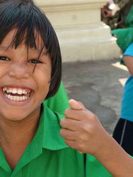 Smiling girl in green shirt giving thumbs up outdoors