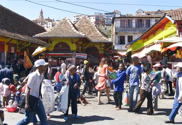 Crowded market with colorful stalls and tiled roofs, people walking in the sun