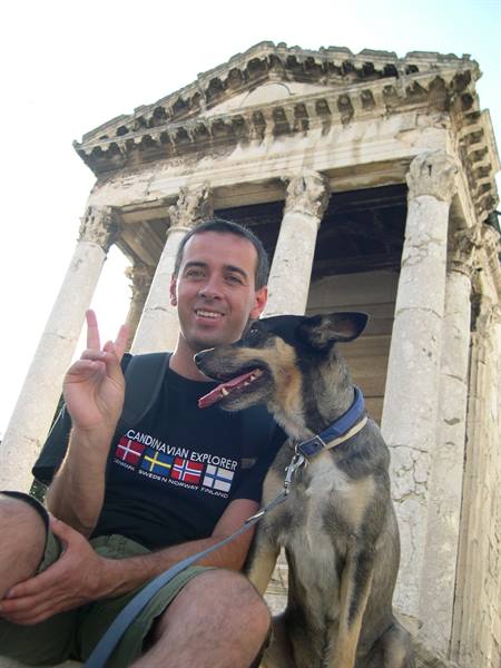 Traveler with his dog at the Temple of Augustus in Pula, flashing peace sign