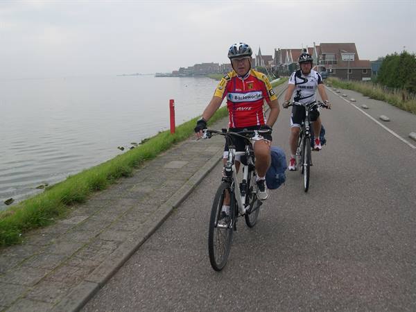 Cyclists ride along a brick waterfront road beside the sea