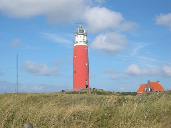 Red Eierland lighthouse on Texel among dune grass under blue sky