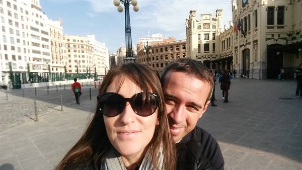 Couple selfie in front of Valencia's Plaça de l'Ajuntament, ornate buildings and sunlight