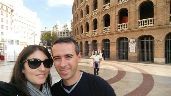 Smiling couple in front of Valencia's Plaza de Toros bullring on a sunny morning