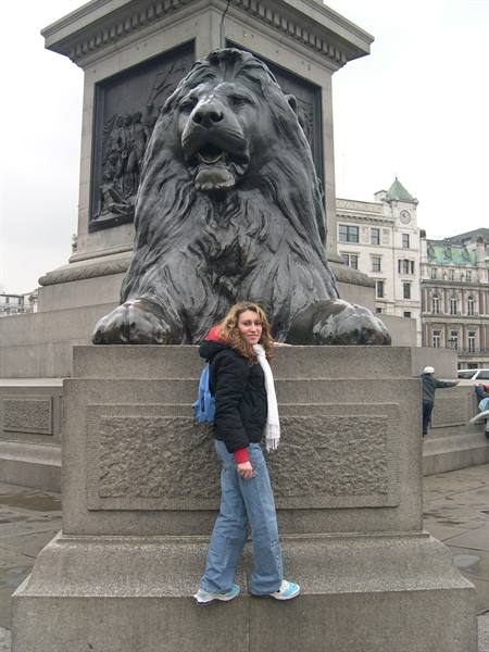 Tourist beside the bronze lion at the column base, Trafalgar Square