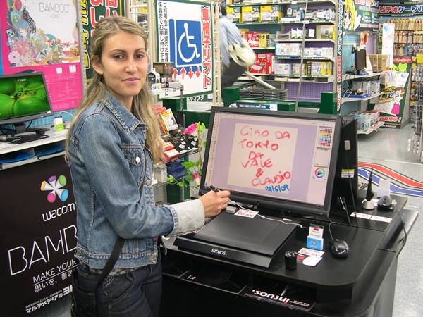 Woman drawing on a Wacom screen in an electronics store, Japanese signs