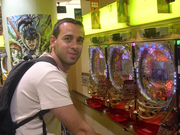 Backpacker next to glowing pachinko machines in a Japanese game arcade