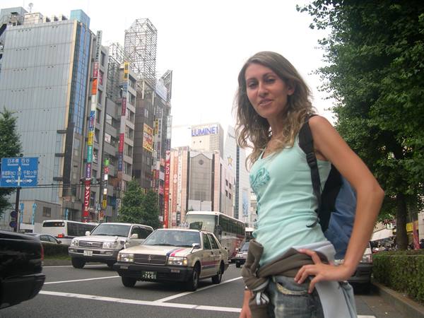 Girl with backpack crossing a busy Shibuya street among taxis and skyscrapers