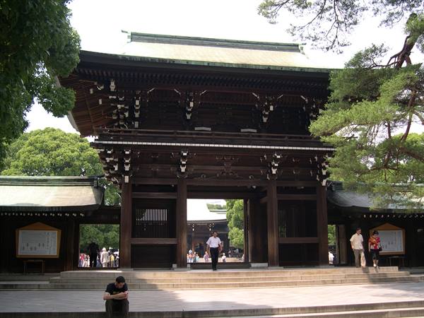 Wooden gate of Meiji Shrine in Tokyo, visitors climbing steps under trees