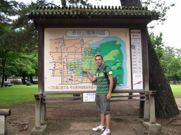 Tourist with backpack points at the wooden map board of Nara Park