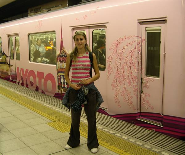 Tourist posing by a pink train decorated with cherry blossoms