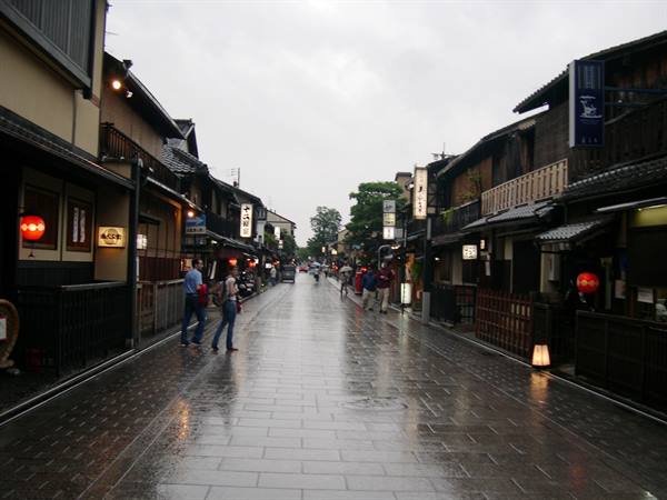 Rain-soaked street in Gion, Kyoto, wooden houses and red lanterns under grey sky