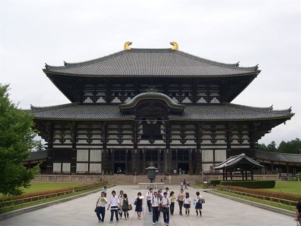 Students walk toward the great Todai-ji temple in Nara, wooden structure and tiled roofs