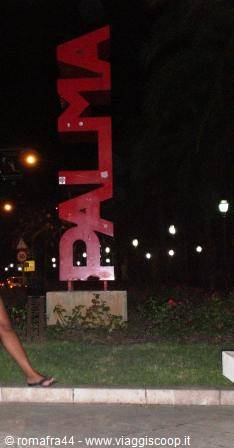 Red Palma sign at night in a lit city garden