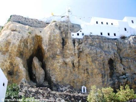 White houses built into volcanic rock, blue-domed church, Santorini