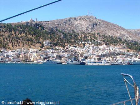 White houses by the harbor, moored ferries, rocky mountain behind