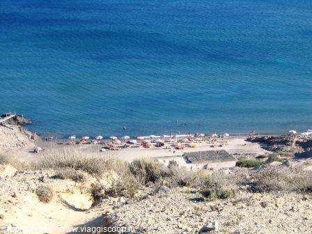 Sandy beach with colorful umbrellas and swimmers on turquoise sea