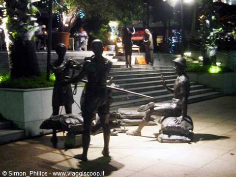 Bronze statues of musicians at night in a lit square in Singapore