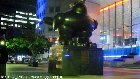 Fernando Botero bronze bird sculpture lit up at night among skyscrapers