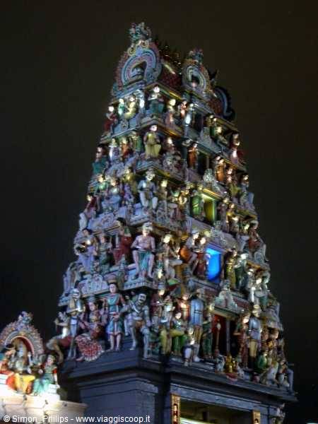 Hindu temple gopuram covered in colorful deity statues, lit at night